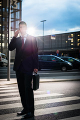 Business man using phone in evening outdoors, picture has strong intentional lens flare