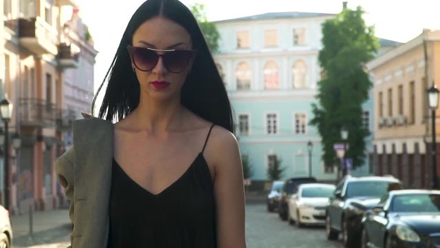Elegance woman in fashionable clothes and sunglasses walking in slow motion
