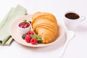 Coffee, fresh croissant with jam and berries for breakfast