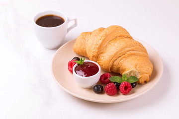 Coffee, fresh croissant with jam and berries for breakfast