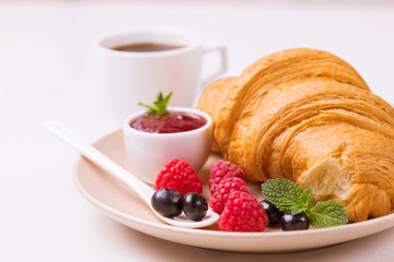 Coffee, fresh croissant with jam and berries for breakfast