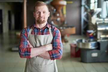 Waist up portrait of modern bearded man wearing apron posing standing confidently with arms crossed...