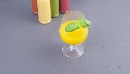Juice in bottles, different and in a glass. Gray background. Detox food. Copy space.
