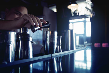 Fototapeta na wymiar Bartender is adding ingredient in shaker at bar counter