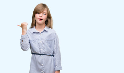 Young blonde toddler wearing blue shirt pointing with hand and finger up with happy face smiling