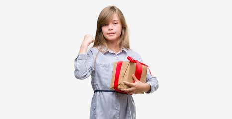 Young blonde toddler holding a present screaming proud and celebrating victory and success very...