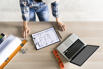 woman civil architech engineer checking blueprint or home plan with laptop on wood...