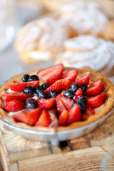 Tart with fresh strawberries and blueberrys on a wooden background