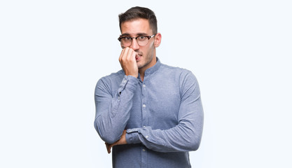 Handsome young elegant man wearing glasses looking stressed and nervous with hands on mouth biting nails. Anxiety problem.