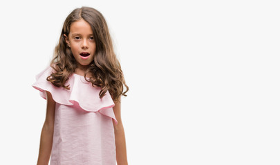 Brunette hispanic girl wearing pink dress afraid and shocked with surprise expression, fear and excited face.