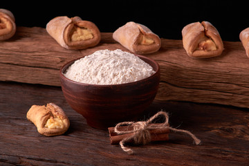 Composition of tasty cottage chees cookies on chopping board with bowl flour and rolling pin. on rustic background