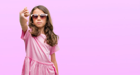 Brunette hispanic girl wearing sunglasses with angry face, negative sign showing dislike with thumbs down, rejection concept