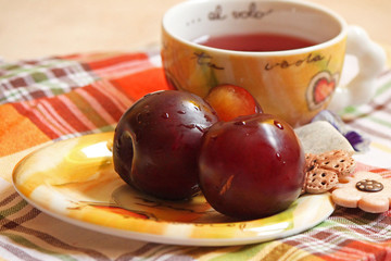 tè ai frutti rossi con susine fiori e pasticcini