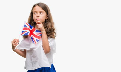 Brunette hispanic girl holding flag of United Kingdom serious face thinking about question, very confused idea