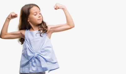 Brunette hispanic girl showing arms muscles smiling proud. Fitness concept.