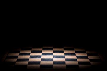 abstract chessboard on dark background lighted with snoot - obrazy, fototapety, plakaty