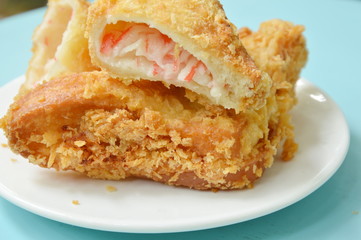 crispy fried sandwich stuffed tuna and imitation crab stick on white plate