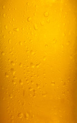 Vertical shot of a beer glass with cold drops falling down. Colorful vibrant orange surface.
