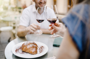 Cheerful couple in a restaurant with glasses of red wine.  Young couple with glasses of red wine in a restaurant with city view
