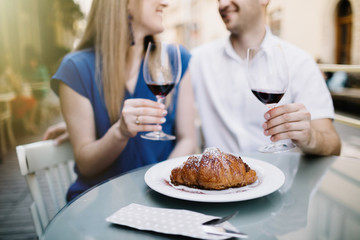 Cheerful couple in a restaurant with glasses of red wine.  Young couple with glasses of red wine in a restaurant with city view