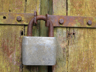 Old rusty padlock on the locked wooden doors. Home security concept