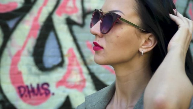 Portrait of stylish brunette in sunglasses touching her hair