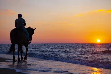 Fotobehang Woman riding a horse on the beach © Elena Blokhina