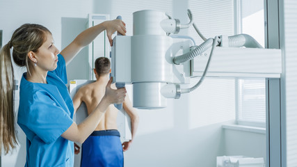 In the Hospital, Man Standing Face Against the Wall While Medical Technician Adjusts X-Ray Machine...