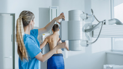 In the Hospital, Man Standing Face Against the Wall While Medical Technician Adjusts X-Ray Machine For Scanning. Scanning for Fractures, Broken Limbs, Chest, Cancer or Tumor. Modern Hospital