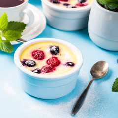 Berry clafouti. Traditional french sweet fruit dessert clafoutis with raspberries and blueberries on blue background. Healthy gluten free food concept.