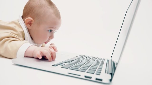 Focused baby girl watching at laptop screen