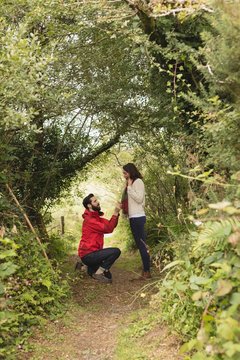 Side view of man proposing to woman in forest