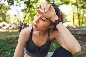 Close up of a tired young fitness girl wiping her forehead