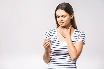 Portrait of a worried young beautiful woman checking her temperature. White background, flu.