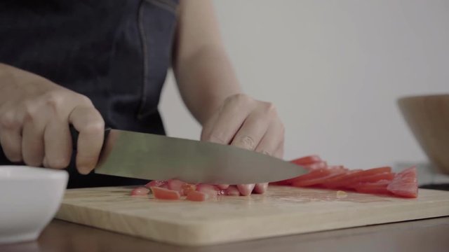 Close up of chief woman making salad healthy food and chopping tomato on cutting board in the kitchen.