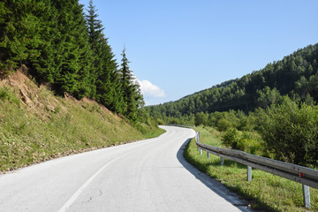 Mountain road. Old road through the forest. Concept of travel under a blue sky