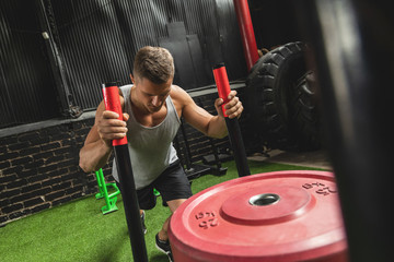Strong sportsman during sled push exercise