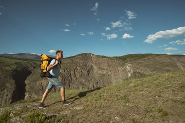 Obraz premium Man goes uphill with a backpack on his back