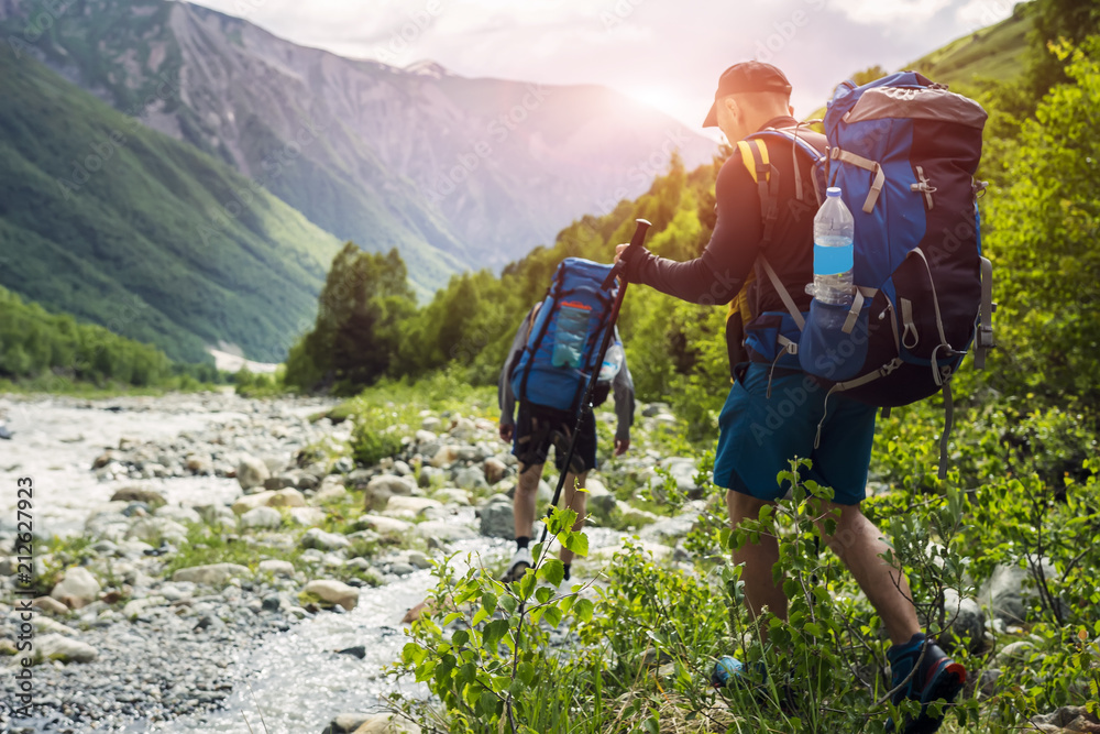 Wall mural tourists with hiking backpacks on beautiful mountain landscape background. climbers hike to mounts. 