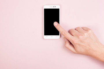Hand with a smartphone on a pink background. Empty space. Finger