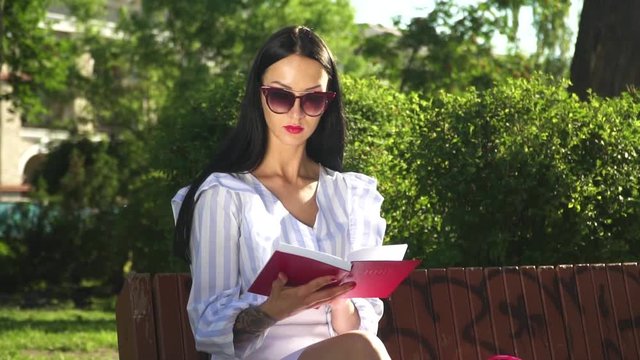 Beautiful woman in sunglasses read book in park