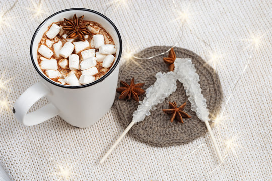 Hot chocolate or cacao with marshmallows in white cup with christmas lights. Winter holiday food. Sweet hot beverage. Copy space.