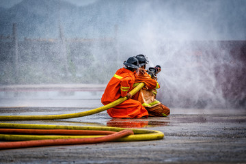 Fireman using water and extinguisher to fighting with fire flame in an emergency situation Car crash .under danger situation all firemen wearing suit for safety.