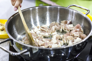 Chef cooks chicken in a large saucepan