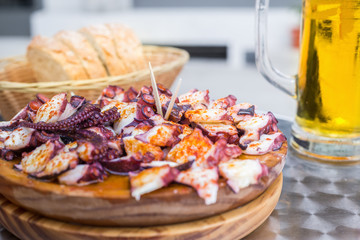 Tasty Wooden plate of galician style cooked octopus with paprika and olive oil. Pulpo a la gallega.