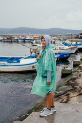 Fototapeta na wymiar Boy in clothes for rain, ashore, among boats