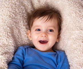 Portrait of a little smiling boy in a blue shirt on a white background