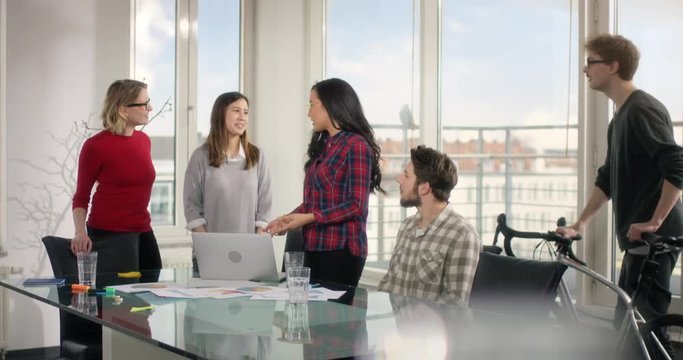 Learning group of students high fiving each other behind a glas desk