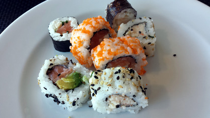 Seven pieces of fresh, colorful sushi on a white plate.