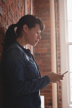 Side view of businesswoman using smartphone while standing in office